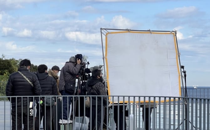 レフ版とカメラを囲むスタッフの撮影風景